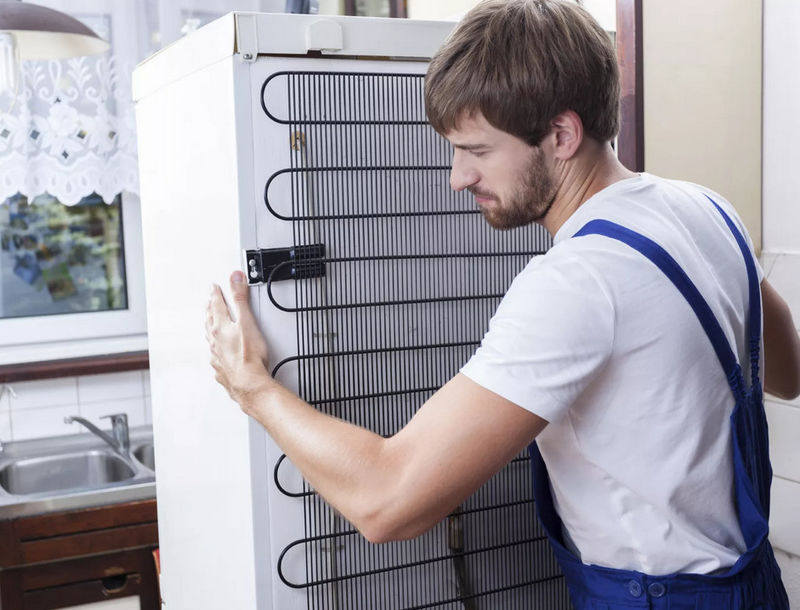 Мастер прикрепляет решетку холодильника